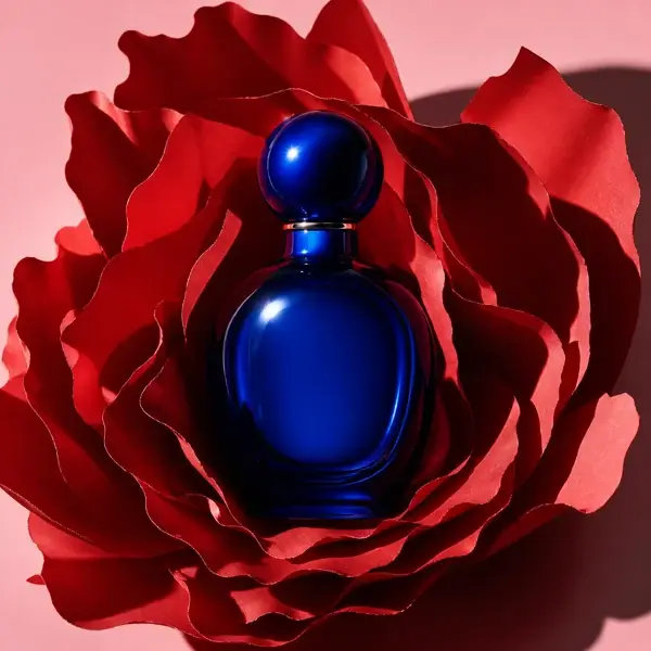 Dark blue perfume bottle surrounded by layered red petals