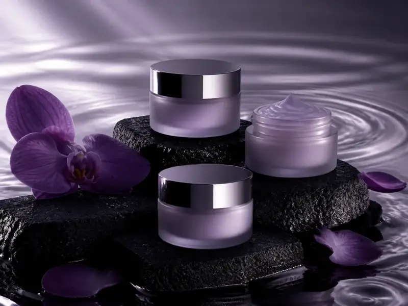 Lavender skincare jars among purple orchids and rippling water