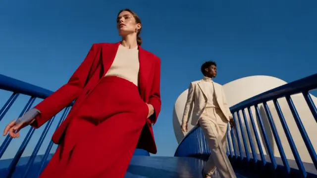 Models in red and ivory suits against modern blue architecture